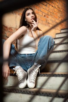 Young woman wearing casual denim jeans and white shirt posing in hall