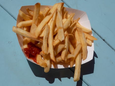 A Portion Of Takeway French Fries On A Camping Table By The Beach