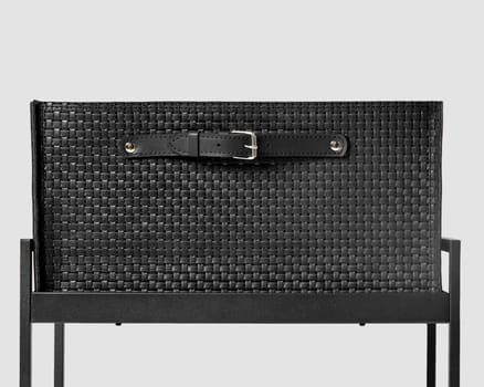 Stylish black leather woven drawer decorated with applied studded strap handle with buckle, placed on shelf in metal office shelving unit. Craft accessory for stationery and document storage