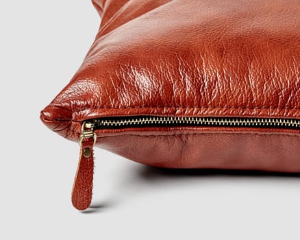 Closeup detailed view of brown leather couch cushion with neat stitching lines and convenient side zipper on white background. Artisanal interior design item