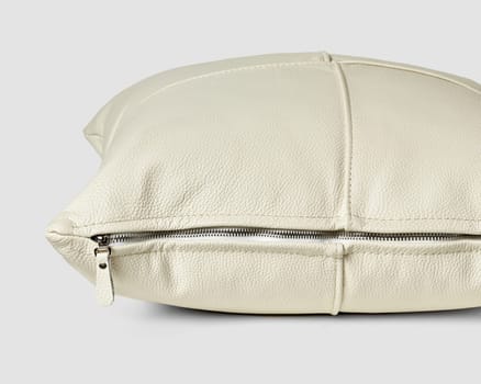 Closeup view of handcrafted sofa pillow made from neatly stitched patches of smooth white genuine leather with metal side zipper for comfort. Stylish artisan accessory for interior design