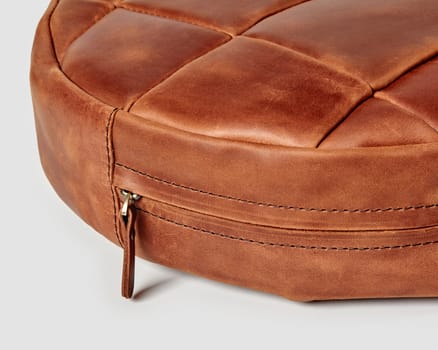 Closeup of decorative round seat cushion made of patches of brown leather with hook-and-loop fastener for comfort and stylish home interior design. Artisanal genuine leather products