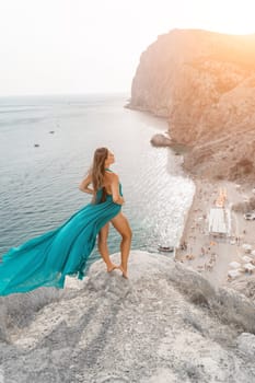 Woman sea trevel green dress. Side view a happy woman with long hair in a long mint dress posing on a beach with calm sea bokeh lights on sunny day. Girl on the nature on blue sky background