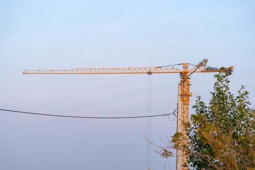 Construction crane stands tall and poised atop a power line in the midst of a bustling city.