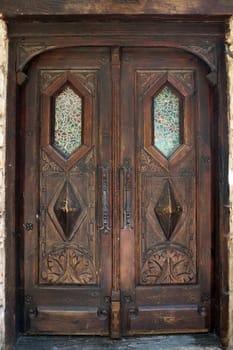 antique, double-leaf, brown entrance door with decor and glass close-up