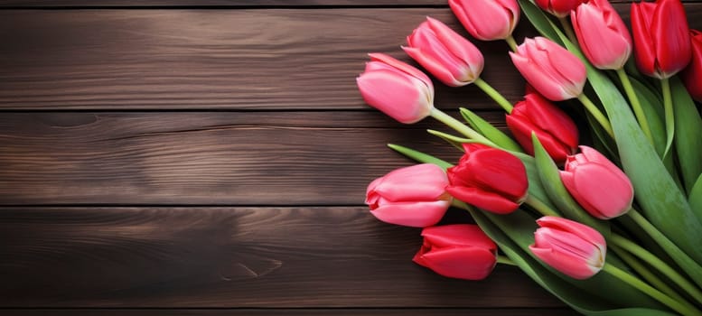 Fresh red tulips laid on a dark wooden surface, creating a contrast of natural beauty and rustic charm.