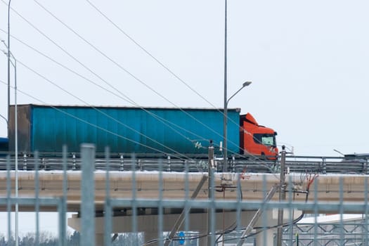 Truck transports a large blue container over a modern bridge, blending into the flow of daily urban traffic.