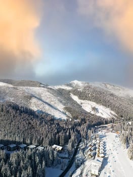 Aerial view of Demanovska Dolina village, snowy forest and mountains in winter. Beautiful panoramic sunset overhead scene of high birds eye view of Low Tatras mountains and woods in Slovakia