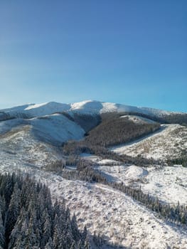 Aerial view of Low Tatras mountains in Slovakia. Winter scenery with rocky skyline and scenic woods, frozen beautiful landscape with ice and snow on pine trees growing on rocks and hills from above