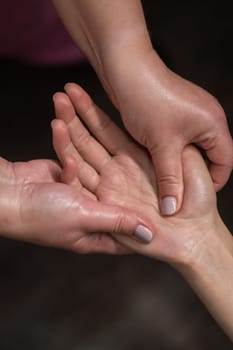 The masseuse massages the client's palms. Close-up of hands during a spa treatment. Vertical photo