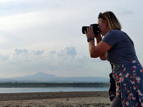 woman traveler taking pictures of mountain lake.