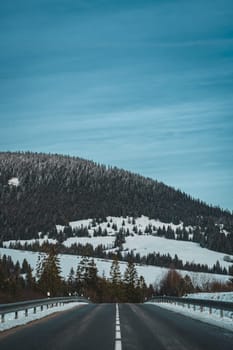 Winter mountain landscape with slippery asphalt road and pine forest, Low Tatras, Slovakia