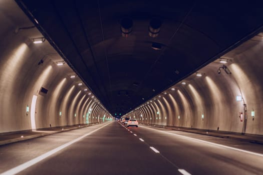 Underground asphalt road tunnel illuminated with yellow lights at night