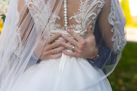 The groom hugs the bride by the waist.