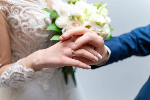 The groom puts a wedding ring on the bride's finger.