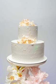 White two-tiered wedding cake decorated with flowers.