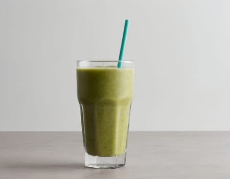 A vibrant green smoothie sits elegantly against a dark backdrop. Garnished with a slice of orange and raspberry a whole pineapple and scattered raspberries accentuate the tropical theme. The image evokes a sense of refreshing indulgence.