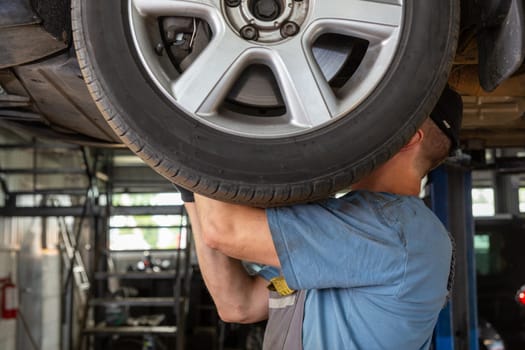 Car mechanic working in auto repair shop. Man in uniform working with car engine.