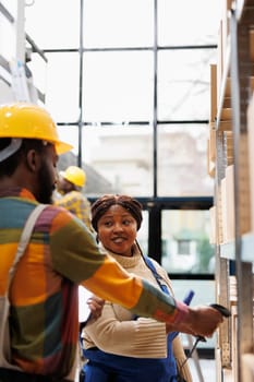 Warehouse supervisor coordinating employee trainee scanning goods packages. African american storehouse operators checking merchandise stock with barcode scanner equipment