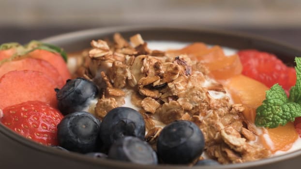 Yogurt with baked granola and berries in small bowl strawberries blueberries. Granola baked with nuts and honey for little sweetness. Slide from left.