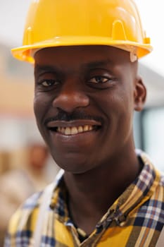 Freight distribution african american smiling worker smiling face portrait. Young man wearing yellow safety industrial helmet looking at camera with optimistic facial expression in warehouse