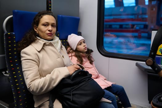 Beautiful family, mother and daughter sitting by passenger window in a high speed train commuting from one city to other. People. Lifestyle. Using raid road transport