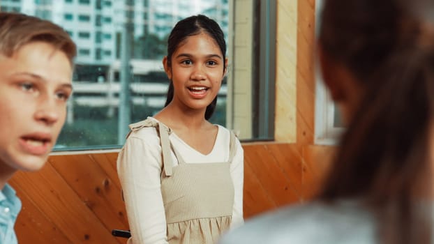 Young student smiling while listening other student in meeting or group discussion. Cute teenager talking about her experience and sharing to friends in mixed races. Creative education. Edification.