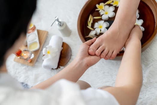 Woman indulges in blissful foot massage at luxurious spa salon while masseur give reflexology therapy in gentle day light ambiance resort or hotel foot spa. Quiescent