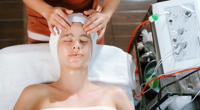 Beautiful young women with beautiful skin having facial massage surrounded by professional therapist using beauty electrical equipment. Top view. Healthy and beauty concept. Tranquility.