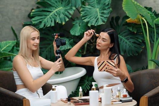 Two beautiful content creator making natural beauty and cosmetic tutorial on green plant garden video. Beauty blogger showing how to beauty care to social medial audience using selfie stick . Blithe