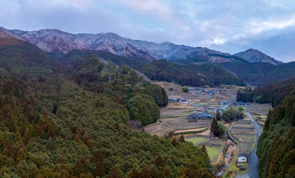 Aerial view of traditional farming village by snow covered mountains. High quality photo