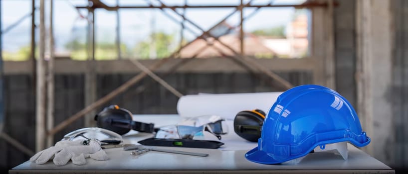 Engineer tool architecture blueprint design and safety helmet hardhat on meeting table with contractors paper project with engineer and architect working and discussing in background.