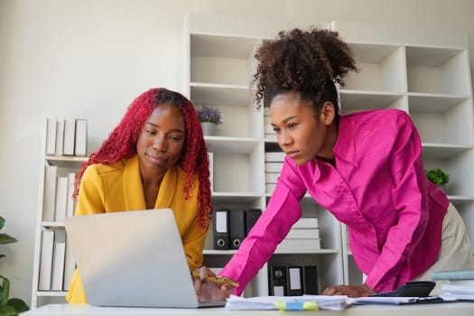 Two businesswoman African American working together using laptop and talking about a business project. team of females executive meeting work in office.