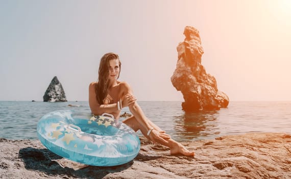 Woman summer sea. Happy woman swimming with inflatable donut on the beach in summer sunny day, surrounded by volcanic mountains. Summer vacation concept