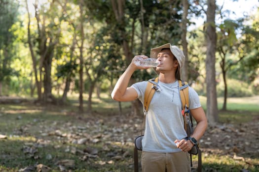 Traveler hiking man carrying a backpack on the back and walking in national park. man asian is rest by drink water.