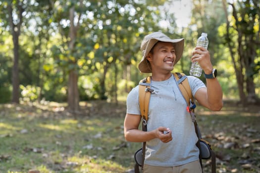 Traveler hiking man carrying a backpack on the back and walking in national park. man asian is rest by drink water.