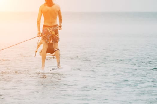 Sea woman and man on sup. Silhouette of happy young woman and man, surfing on SUP board, confident paddling through water surface. Idyllic sunset. Active lifestyle at sea or river