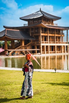 Asian girl in kimono and umbrella in Japanese theme park Hinoki Land in Chai Prakan District, Chiang Mai