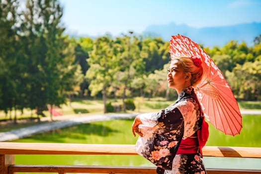 Asian girl in kimono and umbrella in Japanese theme park Hinoki Land in Chai Prakan District, Chiang Mai