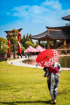 Asian girl in kimono and umbrella in Japanese theme park Hinoki Land in Chai Prakan District, Chiang Mai