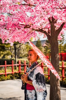 Asian girl in kimono and umbrella in Japanese theme park Hinoki Land in Chai Prakan District, Chiang Mai