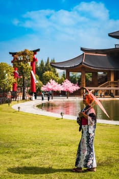 Asian girl in kimono and umbrella in Japanese theme park Hinoki Land in Chai Prakan District, Chiang Mai