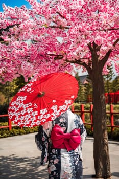 Asian girl in kimono and umbrella in Japanese theme park Hinoki Land in Chai Prakan District, Chiang Mai