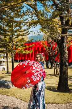 Asian girl in kimono and umbrella in Japanese theme park Hinoki Land in Chai Prakan District, Chiang Mai