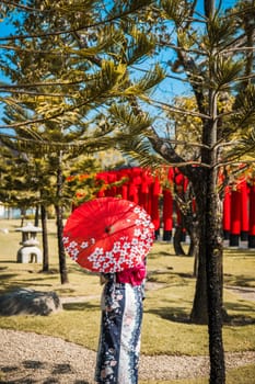 Asian girl in kimono and umbrella in Japanese theme park Hinoki Land in Chai Prakan District, Chiang Mai