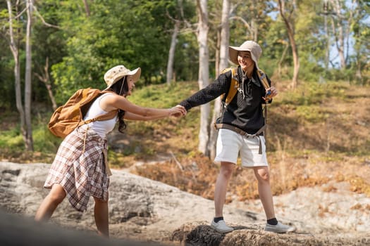 Cheerful romantic lesbian couple traveler with backpack on their backs go hiking through the forest in the mountains in summer.