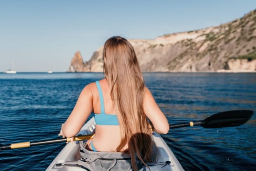 Woman in kayak back view. Happy young woman with long hair floating in transparent kayak on the crystal clear sea. Summer holiday vacation and cheerful female people relaxing having fun on the boat