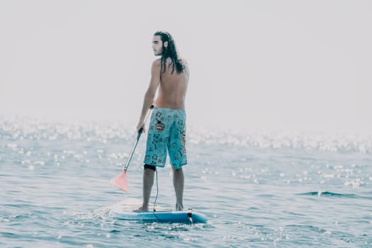 Man Sea Sup. Strong athletic man learns to paddle sup standing on board in open sea ocean on sunny day. Summer holiday vacation and travel concept. Aerial view. Slow motion.