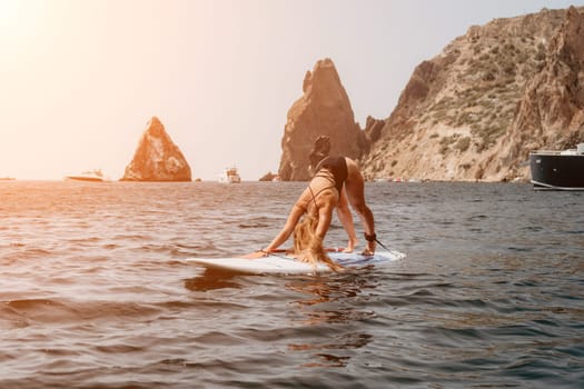 Close up shot of beautiful young caucasian woman with black hair and freckles looking at camera and smiling. Cute woman portrait in a pink bikini posing on a volcanic rock high above the sea