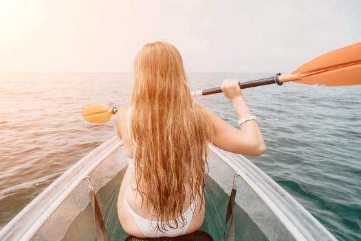 Woman in kayak back view. Happy young woman with long hair floating in transparent kayak on the crystal clear sea. Summer holiday vacation and cheerful female people having fun on the boat.